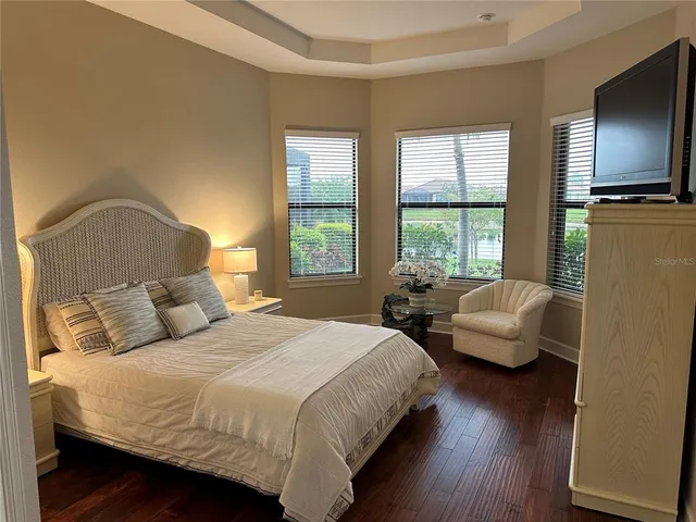 a bedroom with bed couch and wooden floor