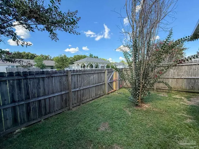 a view of a backyard with wooden fence and a bench