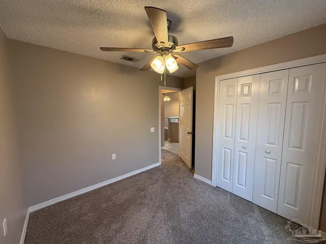 a view of an empty room and a chandelier fan