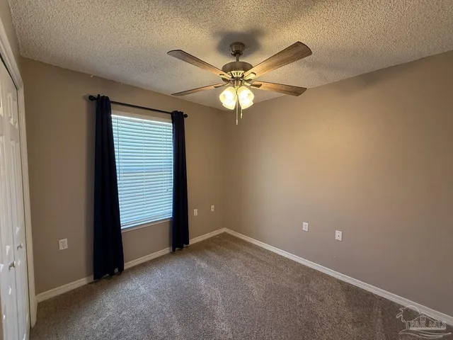 an empty room with windows and fan