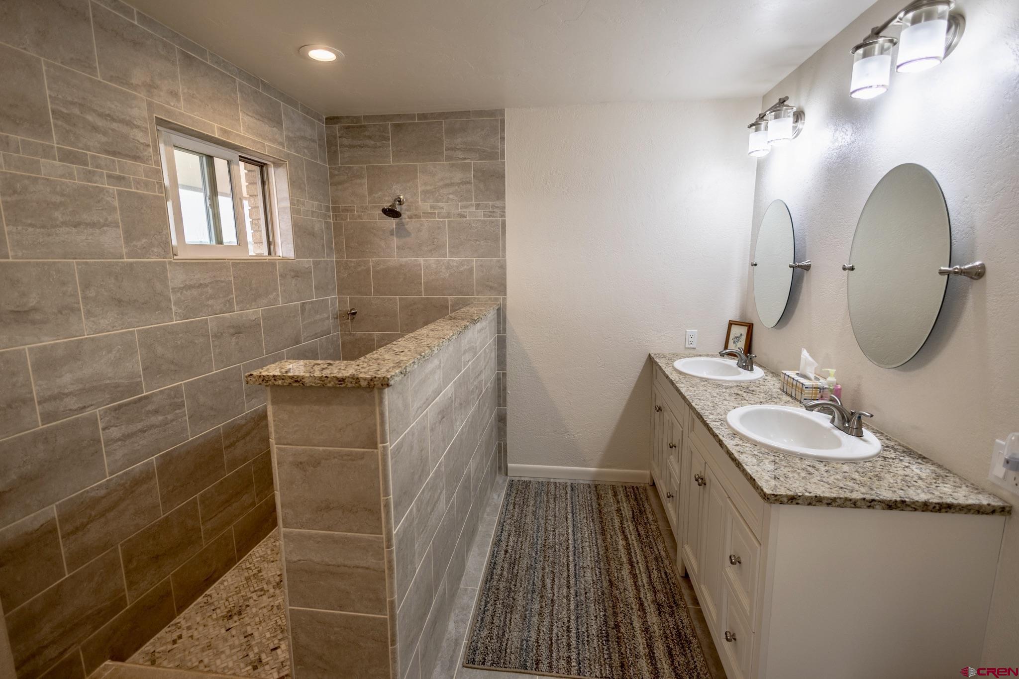 1253 3350th Road Crawford, CO 81415 - Photo 32 of 41 a bathroom with a granite countertop sink a mirror and shower