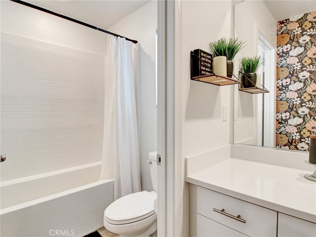 2497 Gunner Ridge Way Rialto, CA 92377 - Photo 35 of 49 a bathroom with a shower curtain a mirror and a toilet