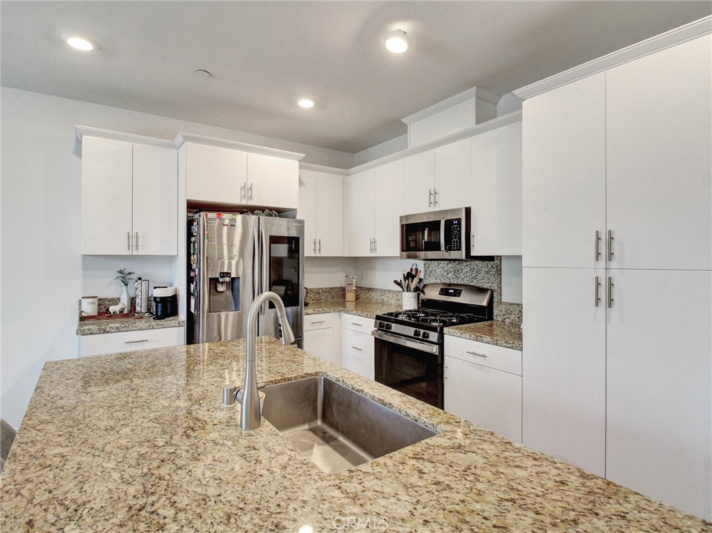 2497 Gunner Ridge Way Rialto, CA 92377 - Photo 8 of 49 a kitchen with stainless steel appliances granite countertop a refrigerator sink and stove