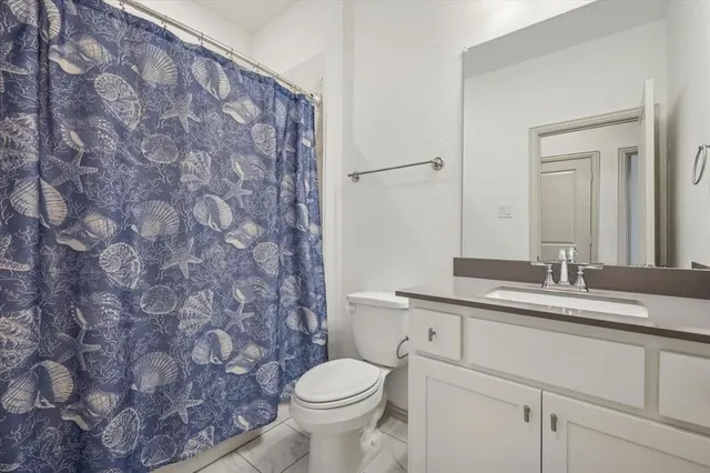 a bathroom with a granite countertop toilet sink and mirror