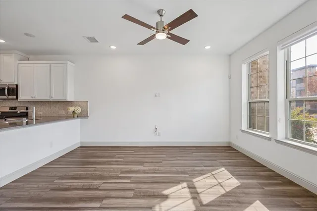 a view of a kitchen with wooden floor and a ceiling fan