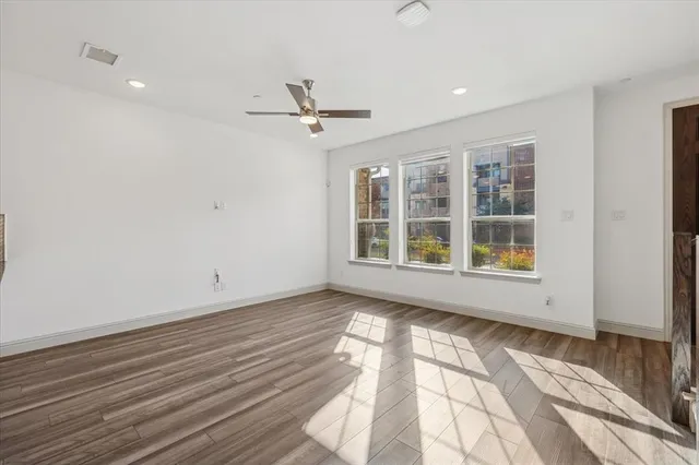 a view of an empty room with a window and wooden floor