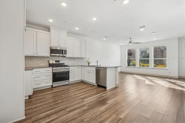 a kitchen with stainless steel appliances kitchen island granite countertop a stove a sink and a refrigerator