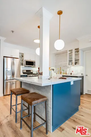 a kitchen with stainless steel appliances kitchen island granite countertop a sink a stove a dining table and chairs