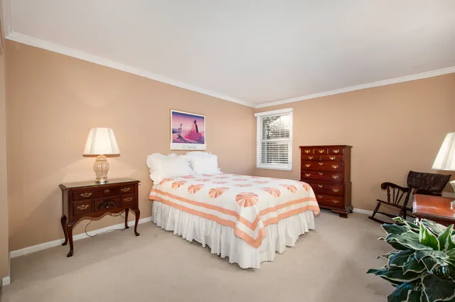 a bedroom with bed and a lamp on dresser