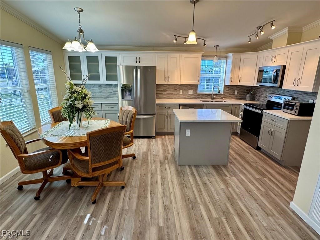 19681 Summerlin Road, Unit 217 Fort Myers, FL 33908 - Photo 6 of 24 a kitchen with kitchen island a dining table chairs wooden floor and a window