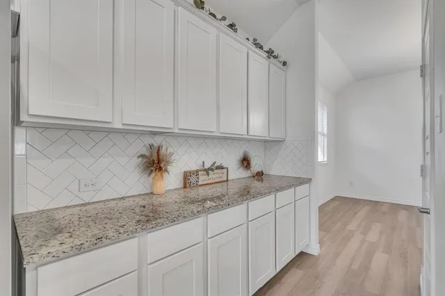 a kitchen with granite countertop white cabinets and sink