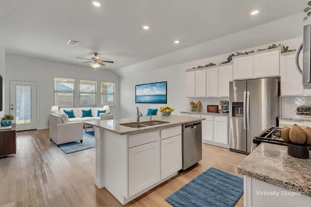 a kitchen with a refrigerator a sink dishwasher with a dining table and chairs