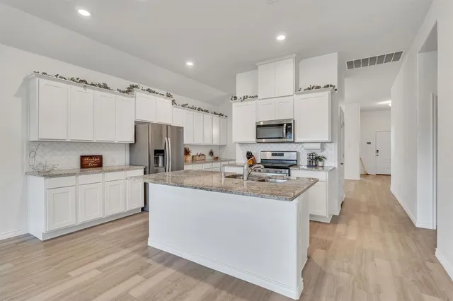 a kitchen with white cabinets stainless steel appliances a sink and a stove