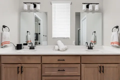 a bathroom with a tub sink double vanity and mirror