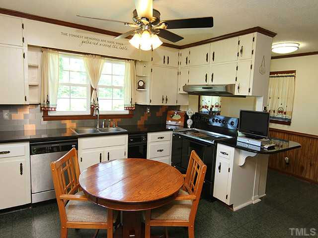 1948 Johnston County Road Benson, NC 27504 - Photo 4 of 13 a kitchen with stainless steel appliances granite countertop a stove a refrigerator a sink a dining table and chairs with wooden floor