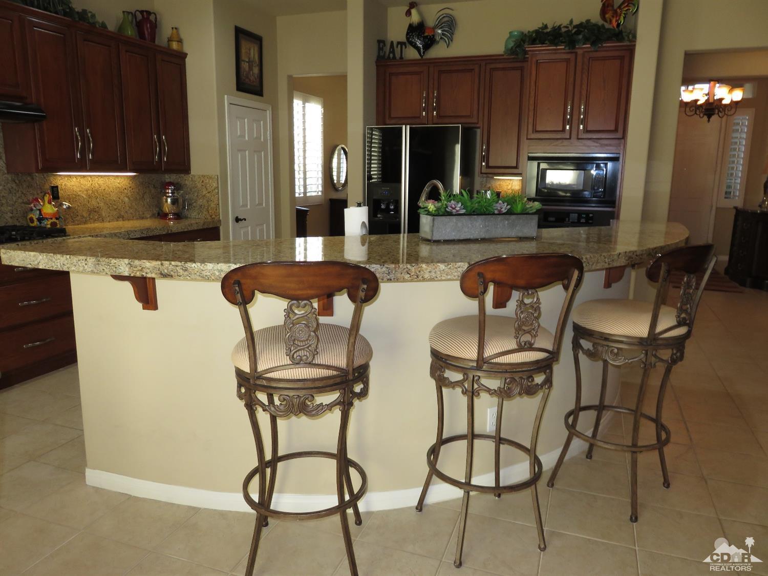 80567 Knightswood Road Indio, CA 92201 - Photo 22 of 57 a kitchen with stainless steel appliances a dining table chairs and a refrigerator