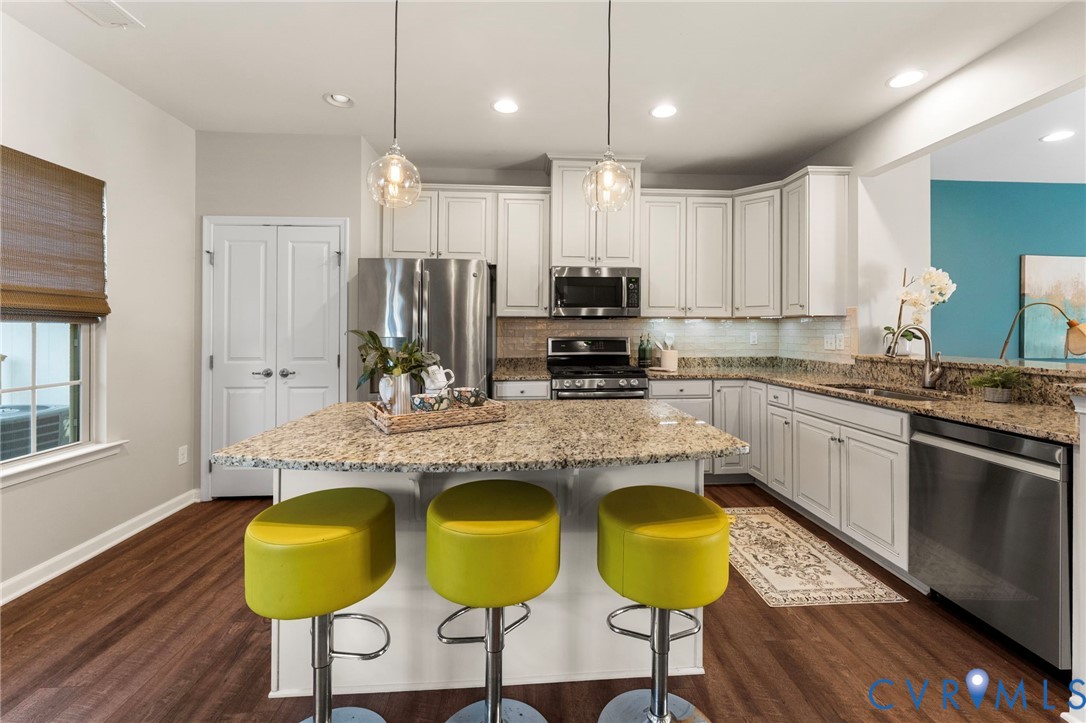 5504 Riverside Heights Way Richmond, VA 23225 - Photo 7 of 29 a kitchen with granite countertop kitchen island stainless steel appliances a stove a sink and a refrigerator
