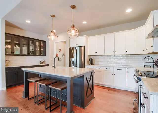 a kitchen with stainless steel appliances a dining table chairs and white cabinets