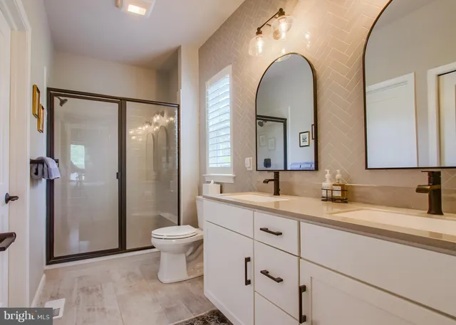 a bathroom with a double vanity sink toilet and a mirror