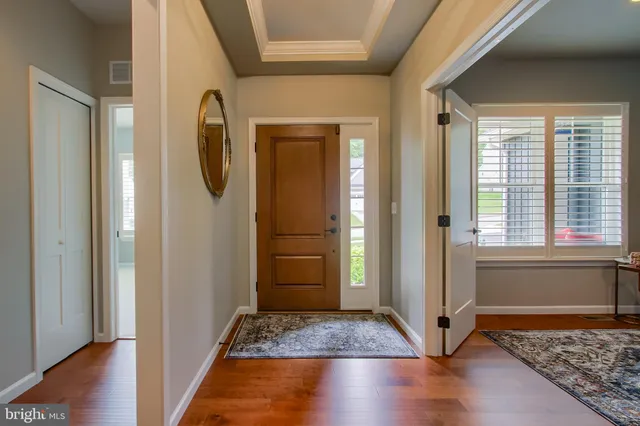 a view of front door with hallway and wooden floor