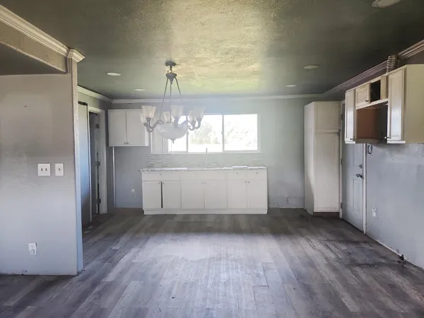 an empty room with wooden floor and a kitchen