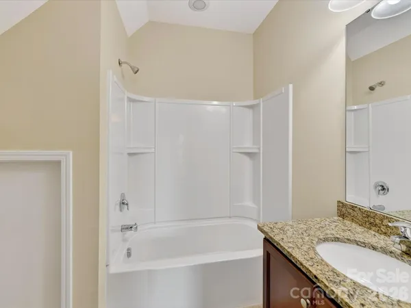 a bathroom with a granite countertop sink a mirror and a bathtub