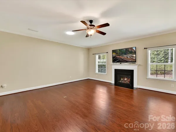 an empty room with windows fireplace and wooden floor