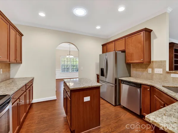 a kitchen with stainless steel appliances granite countertop a refrigerator a sink a stove and wooden cabinets