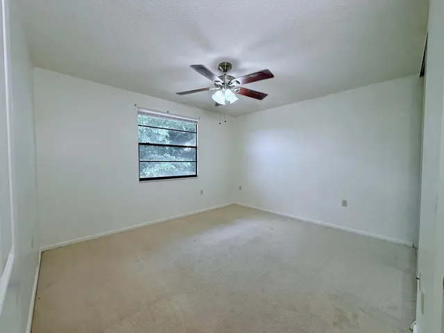 an empty room with a chandelier fan and windows