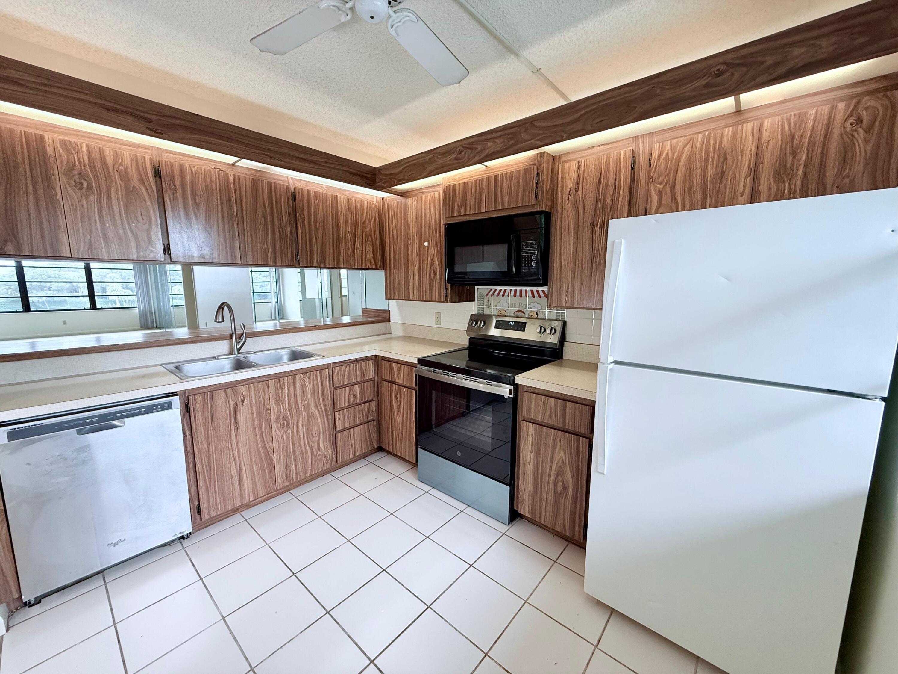 3525 Village Boulevard, Unit 401 West Palm Beach, FL 33409 - Photo 2 of 23 a kitchen with a refrigerator sink and cabinets
