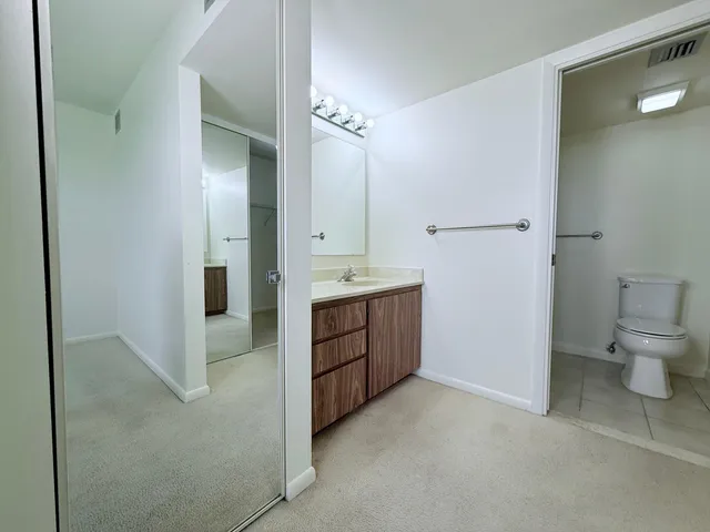 a spacious bathroom with a granite countertop sink a toilet and a mirror
