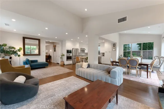 a living room with furniture kitchen view and a large window