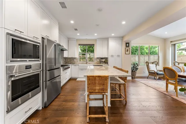 a large kitchen with stainless steel appliances granite countertop a stove a refrigerator a kitchen island a couches and chairs