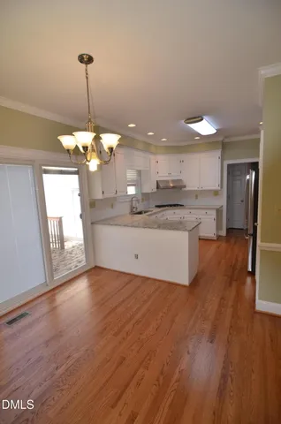 an empty room with wooden floor chandelier fan and closet area
