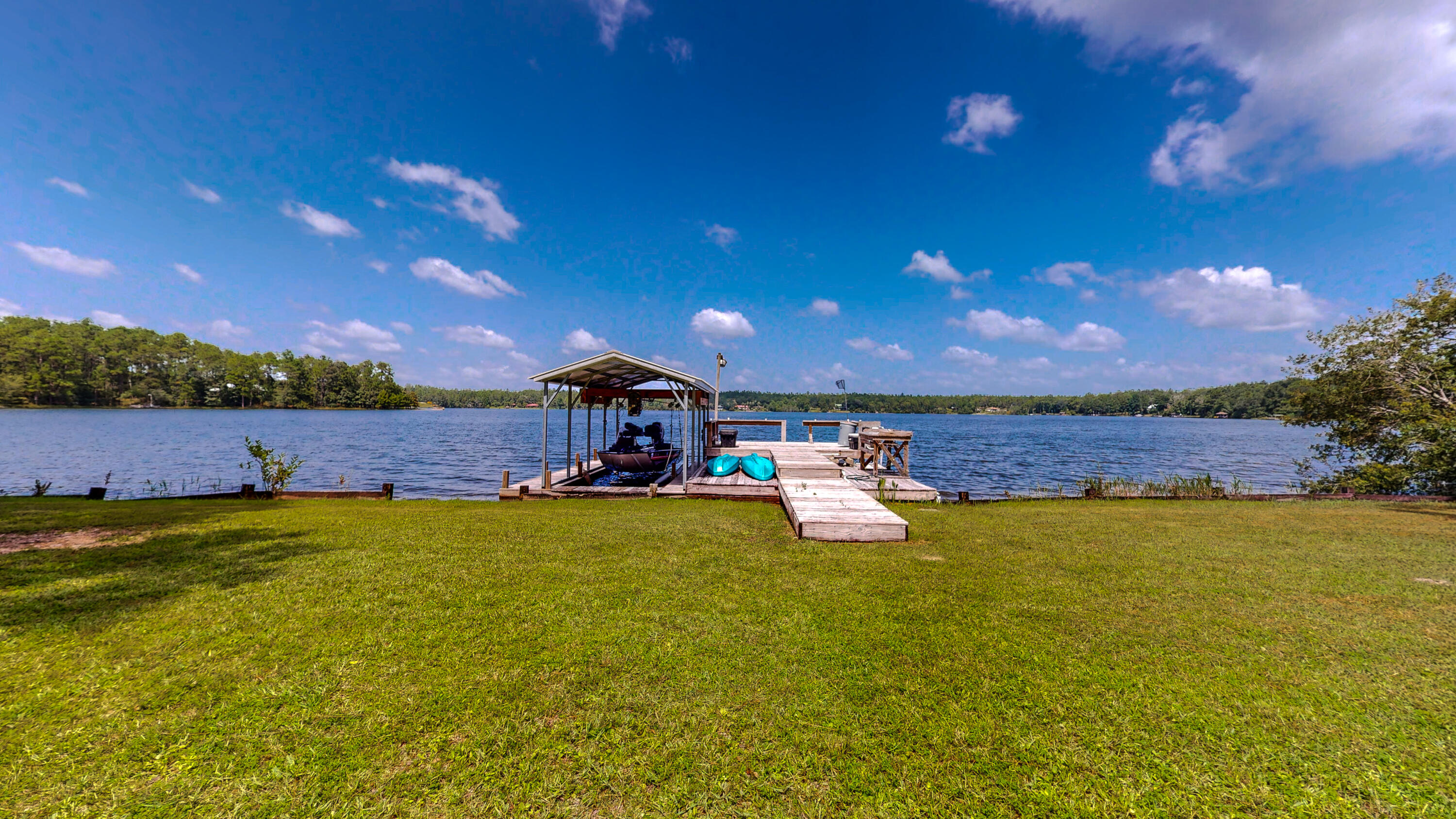 83 Launch Road DeFuniak Springs, FL 32433 - Photo 48 of 62 a view of a lake with lawn chairs and large tree