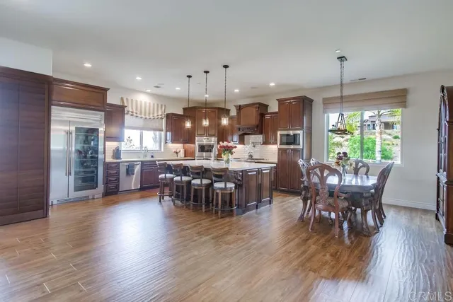 a dining room with stainless steel appliances wooden floors a table and chairs