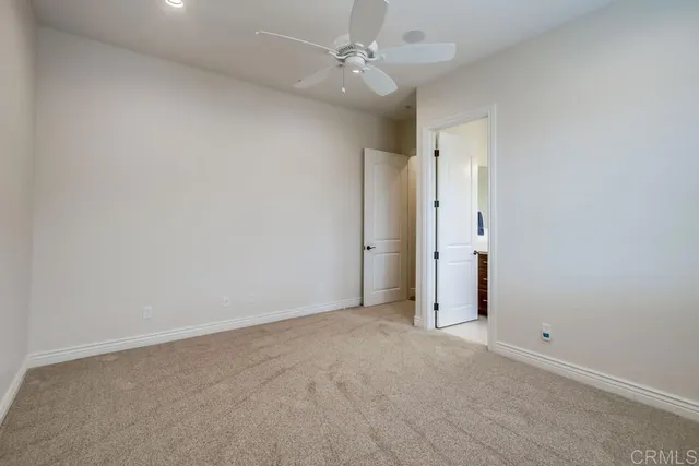 an empty room with a ceiling fan and closet area