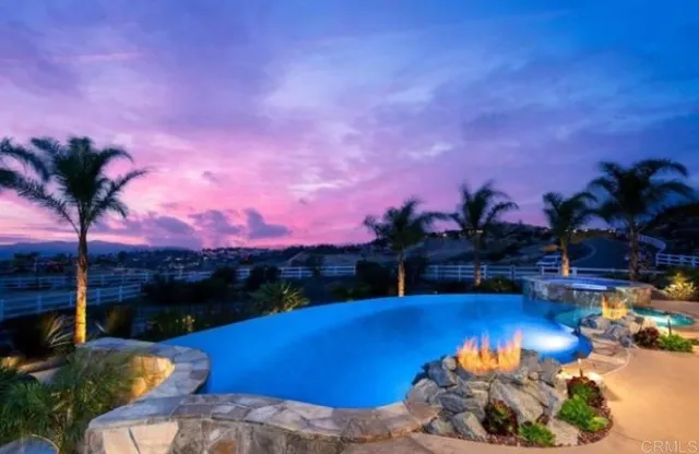 a view of a swimming pool with a table and chairs under an umbrella