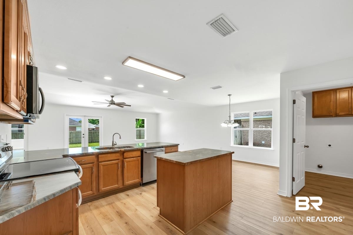 16927 Sugar Loop Foley, AL 36535 - Photo 8 of 50 Kitchen with appliances with stainless steel finishes, brown cabinets, dark countertops, light wood finished floors, and recessed lighting
