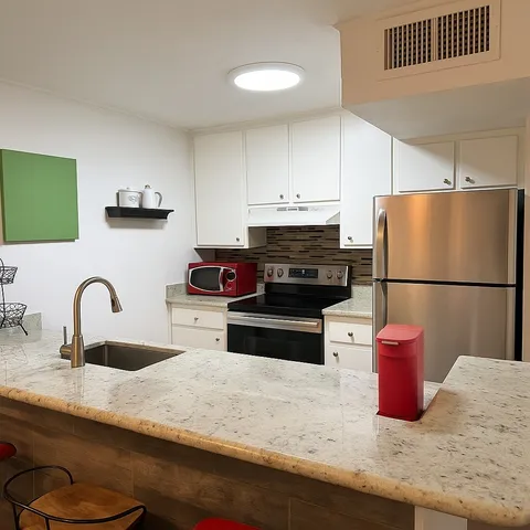 a kitchen with stainless steel appliances granite countertop a sink dishwasher a refrigerator and a stove