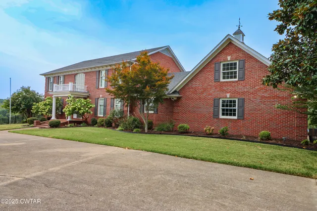a front view of a house with a yard and trees