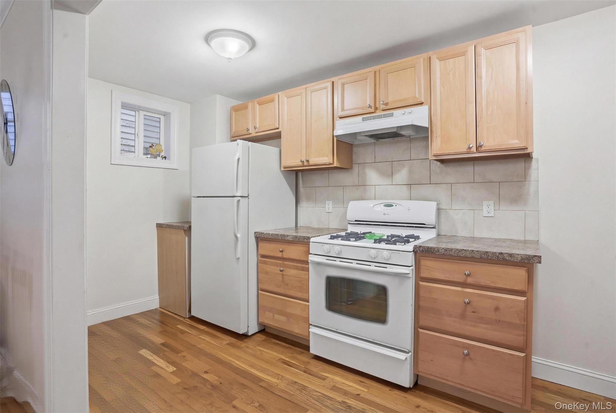 106 Newport Bridge Road, Unit 1 Warwick, NY 10990 - Photo 3 of 6 Kitchen featuring wood-finish flooring, light wood cabinetry, stone-look countertops, and a tile backsplash