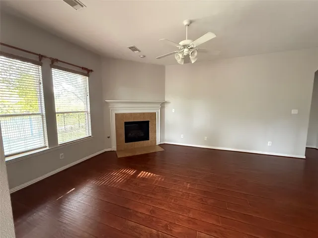 an empty room with wooden floor fan and windows