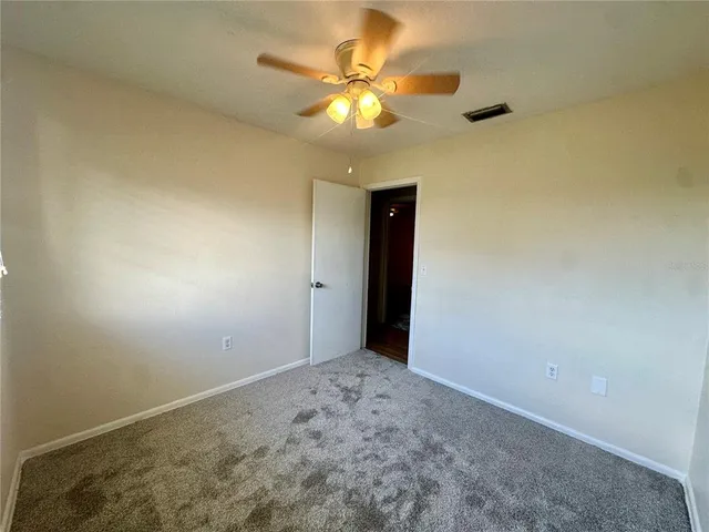 a view of an empty room and chandelier fan