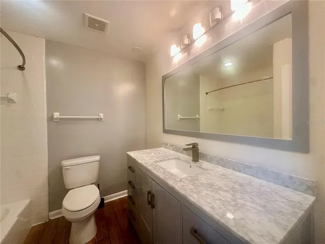 a bathroom with a granite countertop toilet sink and mirror