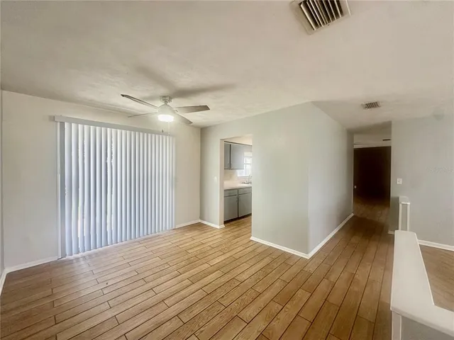 a view of a room with wooden floor and a ceiling fan
