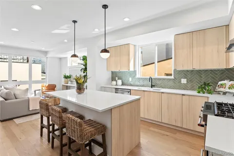 a kitchen with stainless steel appliances granite countertop a stove a sink a center island a stove and a wooden floor