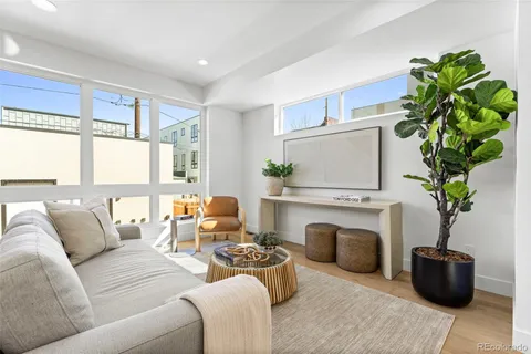 a living room with furniture potted plant and kitchen view