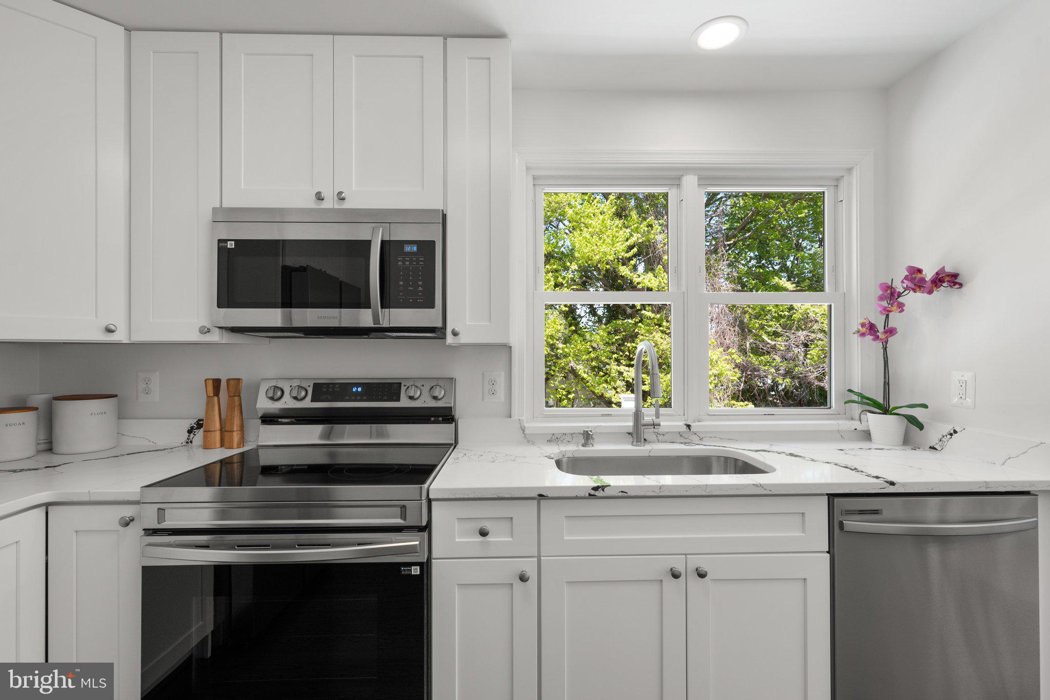 10126 Renfrew Road Silver Spring, MD 20901 - Photo 13 of 40 a kitchen with stainless steel appliances a stove a sink a microwave cabinets and a window
