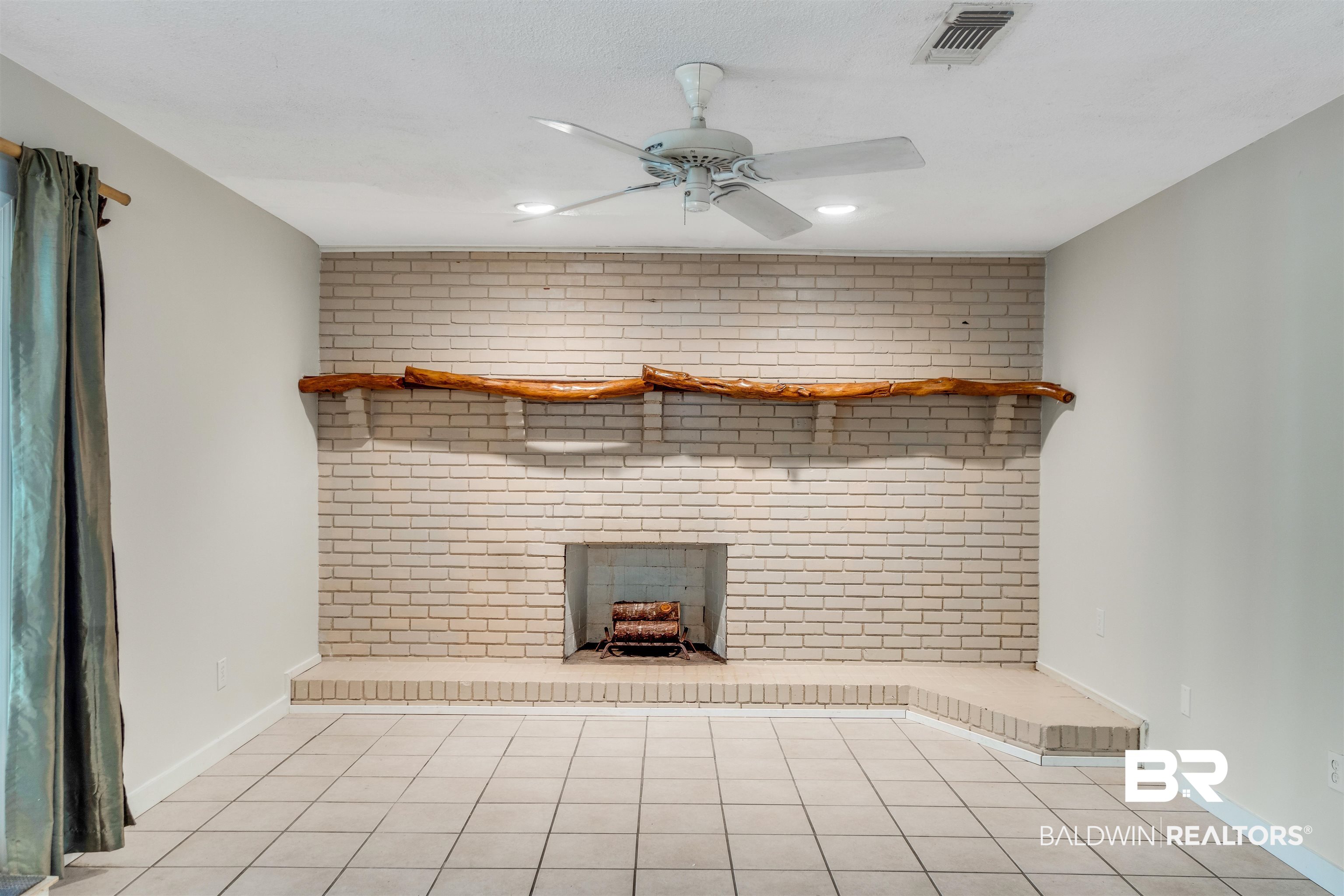 34341 Lost River Road Seminole, AL 36574 - Photo 7 of 36 Unfurnished living room with ceiling fan, a brick fireplace, light tile patterned floors, and brick wall